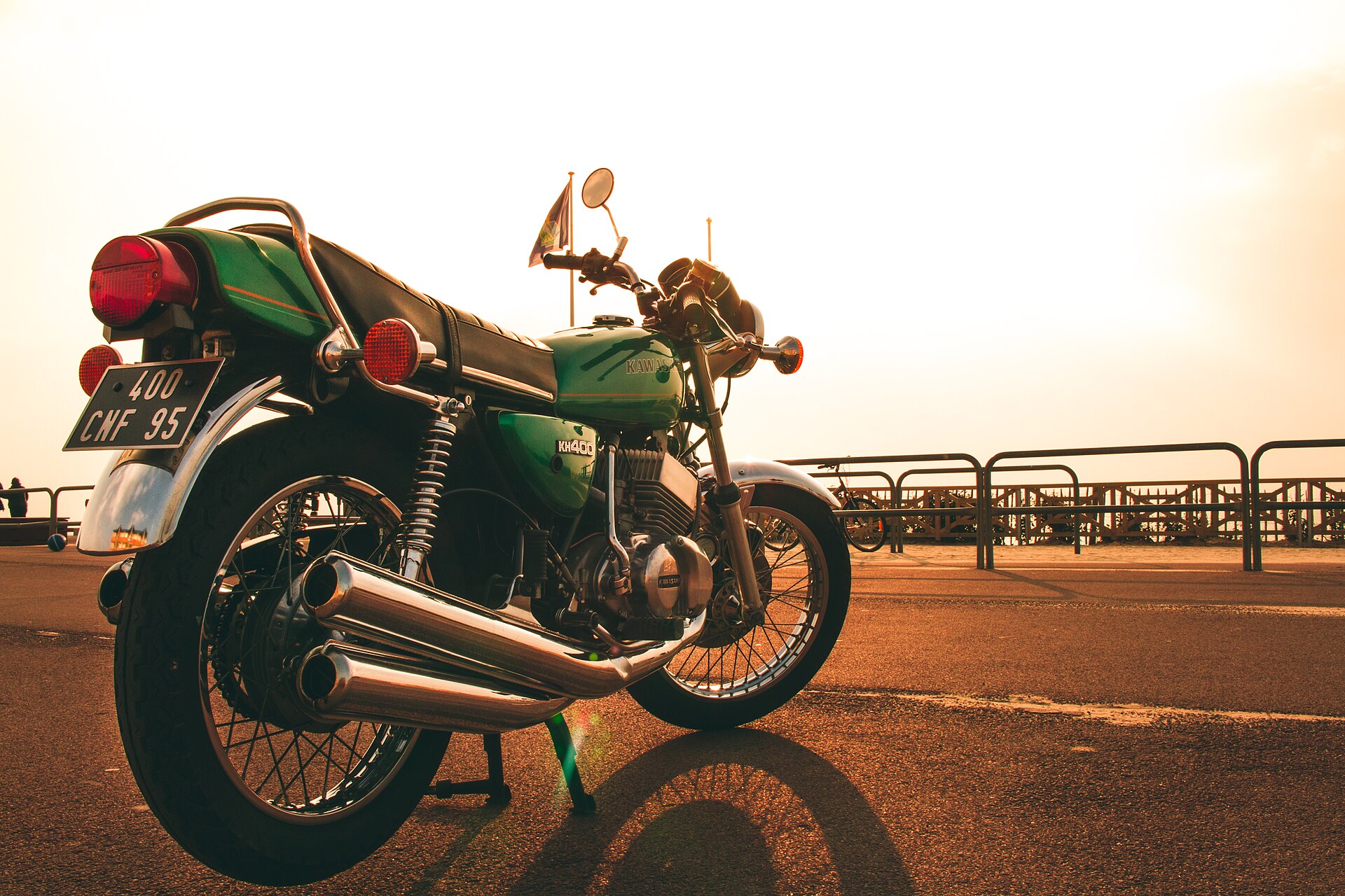 A green Kawasaki motorcycle photographed against a low sun